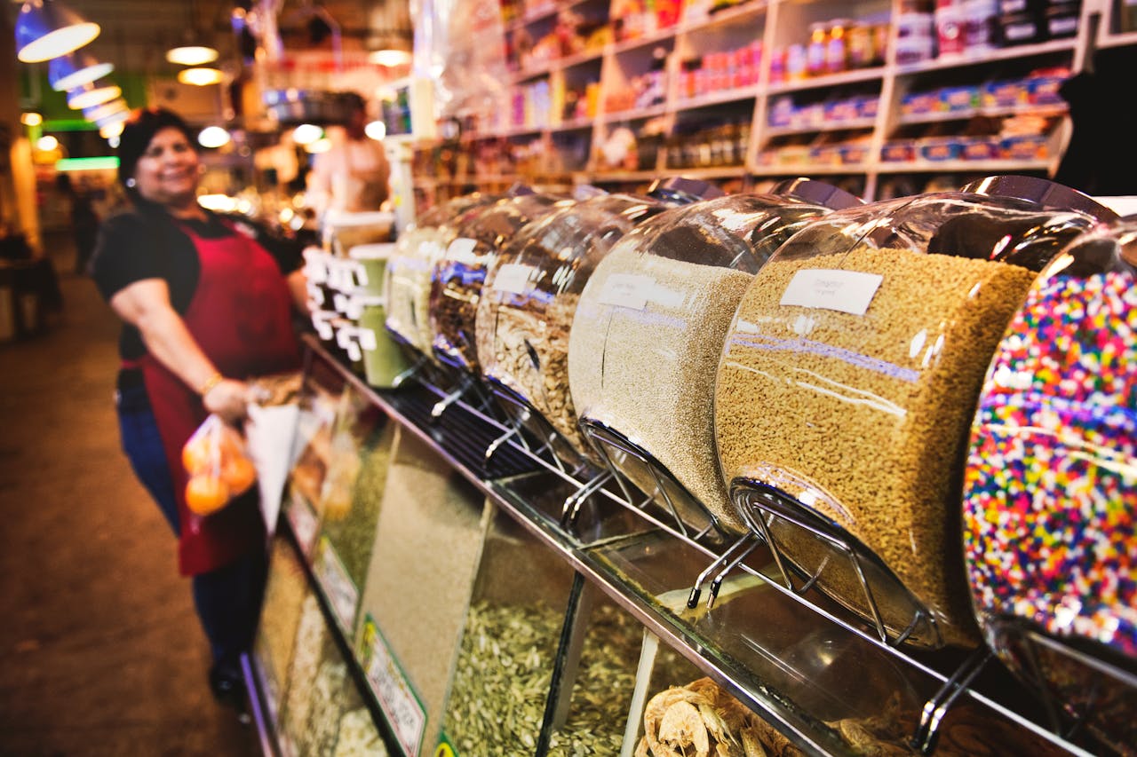 A bustling indoor market showcasing bulk goods with a friendly saleswoman.